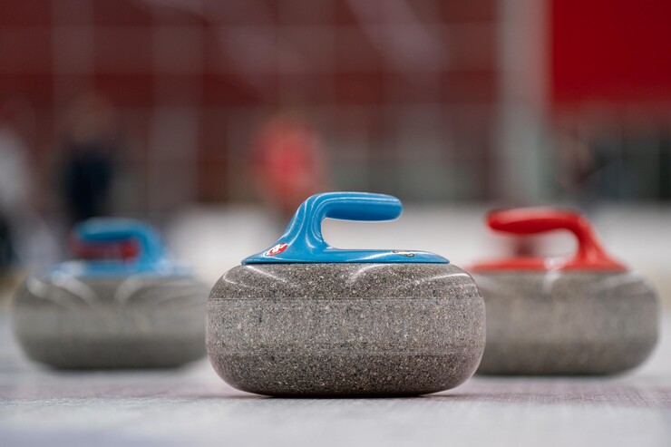 Three curling stones sit on the ice.