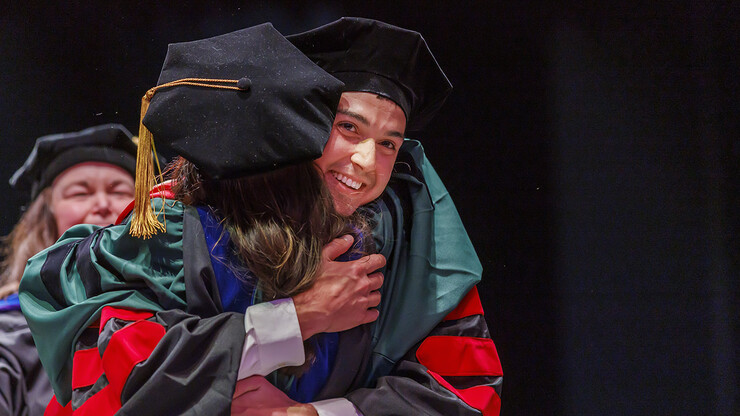 Doctoral graduate Nick Harp hugs his adviser, Maital Neta, after receiving his degree during the graduate and professional degree ceremony May 13 at Pinnacle Bank Arena.