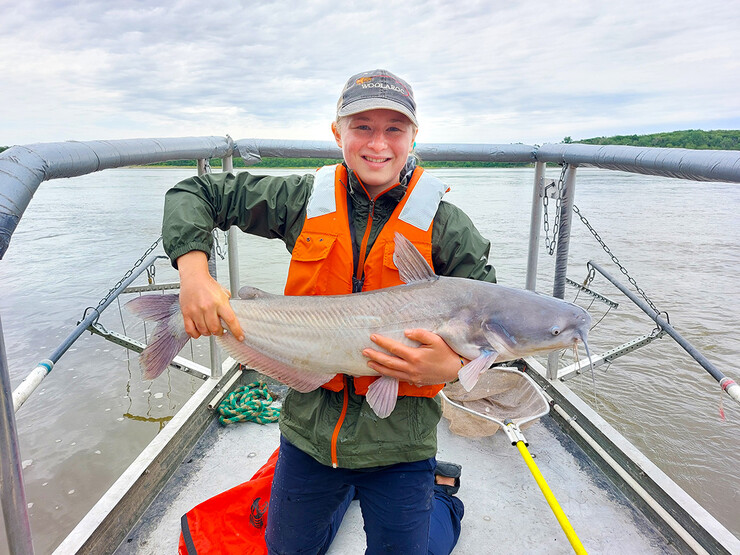 Ella Humphrey, a sophomore in Fisheries and Wildlife, holds a blue catfish taken from the Platte River while working during the summer of 2022 as a fisheries field technician.