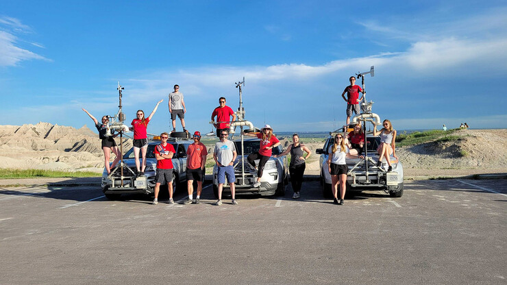 Thirteen members of the TORUS team pose around three stormchasing SUVs in the Badlands.