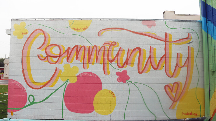 A mural featuring the word "community" in cursive, surrounded by the words "hope," "hardworking," "selflessness," "generosity," "unity" and "inspiration."