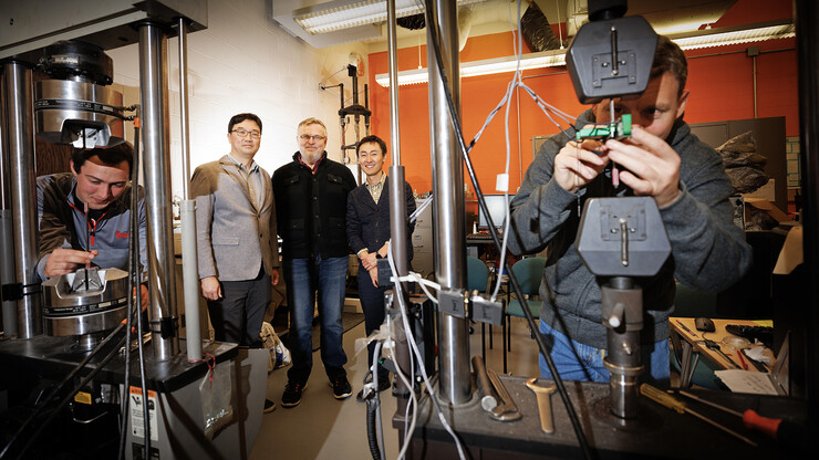 Husker engineers Jongwan Eun (center left), Yuris Dzenis (center) and Seunghee Kim (center right) pose in Dzenis’ lab as Benjamin Bashtovoi (left), a junior mechanical engineering major, and Mikhail Kartashov (right), an engineering graduate student, test carbon-fiber samples. Eun, Dzenis and Kim have received $675,000 from the Department of Energy’s Established Program to Stimulate Competitive Research to investigate how inorganic microfibers can make a more resilient barrier material to improve the long-term storage capabilities of vessels that contain high-level nuclear waste and spent nuclear fuel.