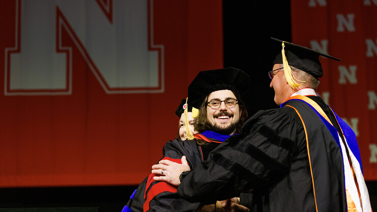 Nate Korth smiles to friends and family as he is congratulated by adviser Andy Benson on his doctoral degree.