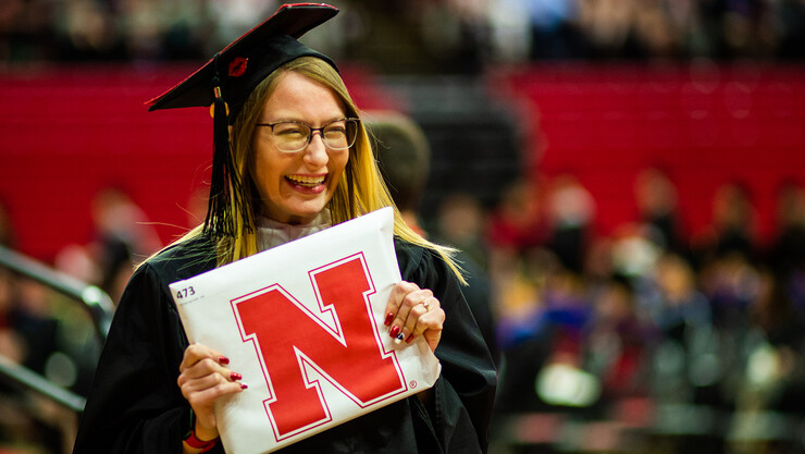 Christa Rahl smiles as she holds her newly earned Master of Arts during the graduate and professional degree ceremony May 19 at the Bob Devaney Sports Center.