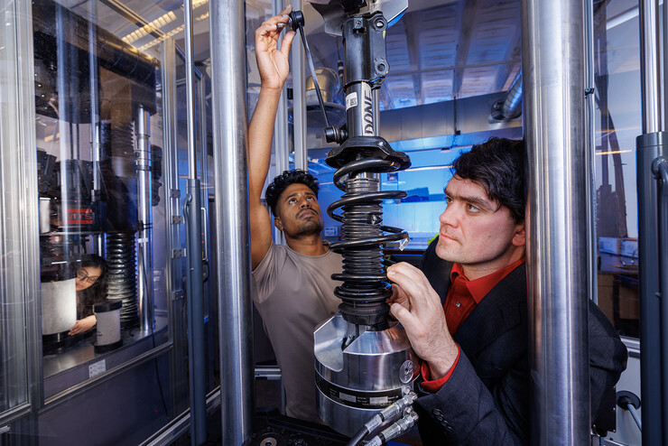 Cody Stolle (right) and Gnyarienn Selva Kumar (center) work on setting up a strut for a compression test while Doreen Rahman (left) does the same for a concrete sample.