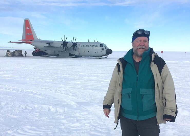 David Harwood, on the Antarctic ice, with a U.S. Air Force plane in the background.