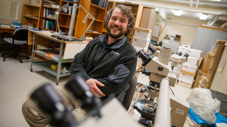 Postdoctoral researcher Jason Coenen sits near microscopes in a University of Nebraska–Lincoln lab.