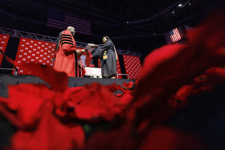 Chancellor Rodney D. Bennett hands a diploma to Marlenia Thornton on stage at Pinnacle Bank Arena.