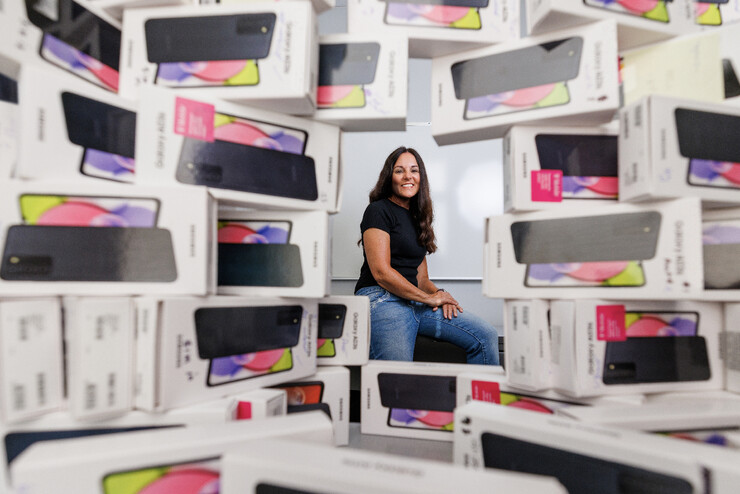 Kimberly Tyler sits behind stacks of smartphone boxes.