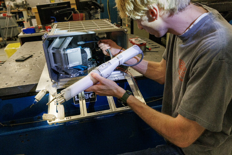 Sean Crimmins, a senior mechanical engineering major, loads the robotic arm into its case before a shake test.