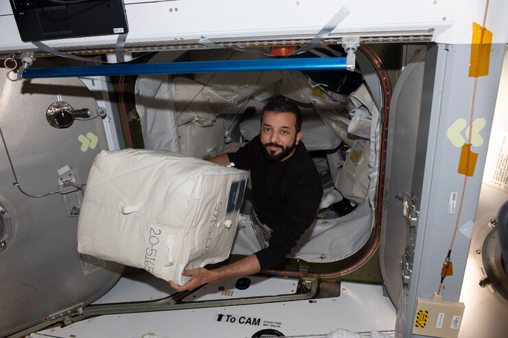 An astronaut unloads a box on the International Space Station.
