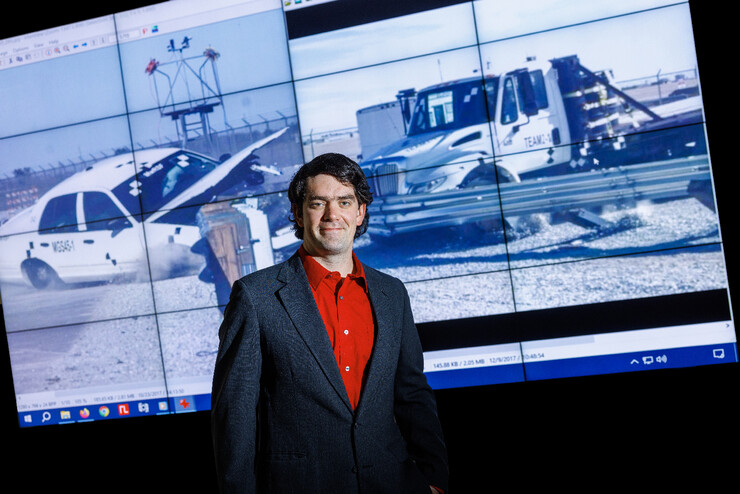 Cody Stolle stands in front of an image of a crash test.