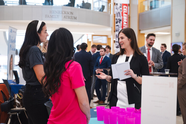 Students in business attire interact with corporate partners in the Henrickson Family Atrium in Hawks Hall.