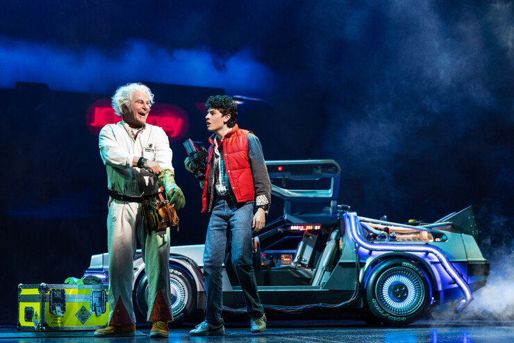 Doc Brown and Marty McFly stand next to a DeLorean.