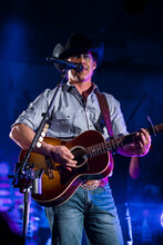 Aaron Watson plays a guitar and sings onstage.