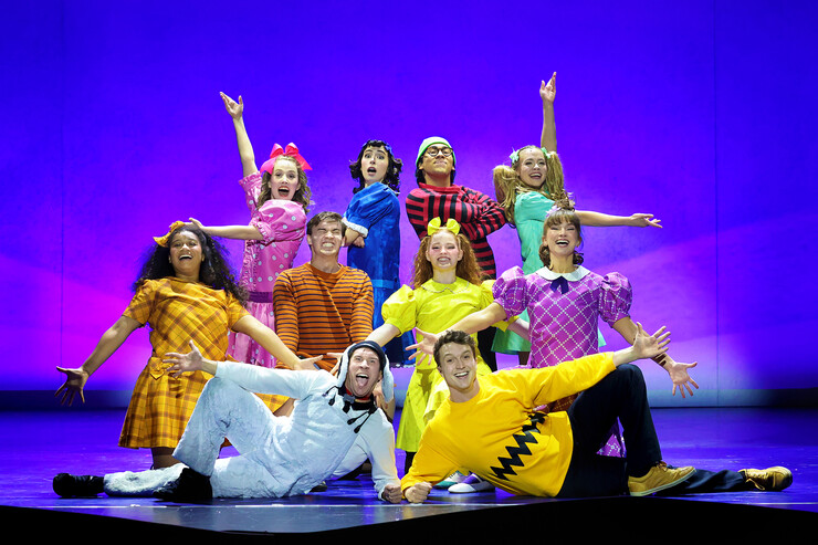 Ten performers pose as the Peanuts gang onstage.