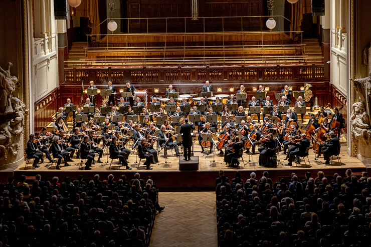 A symphony performs onstage in front of a crowd.