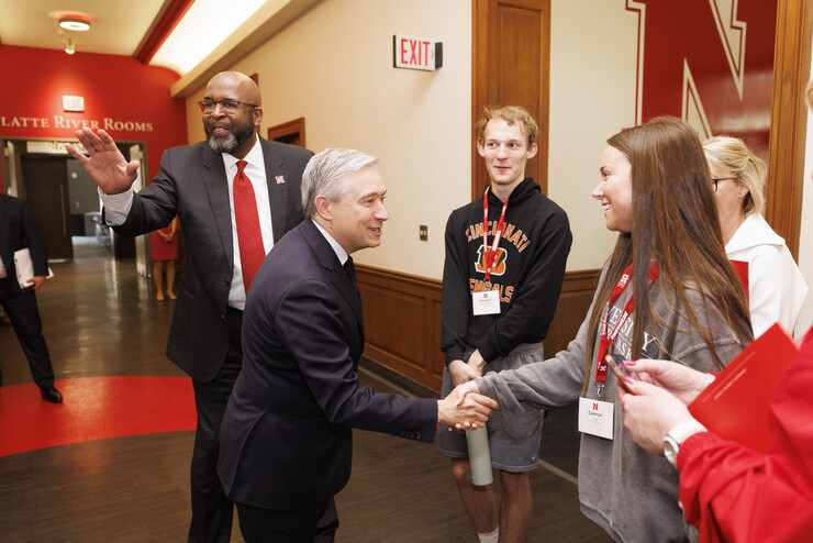 François-Philippe Champagne shakes hands with high school students in the Nebraska Union, as UNL Chancellor Rodney D. Bennett waves behind him.