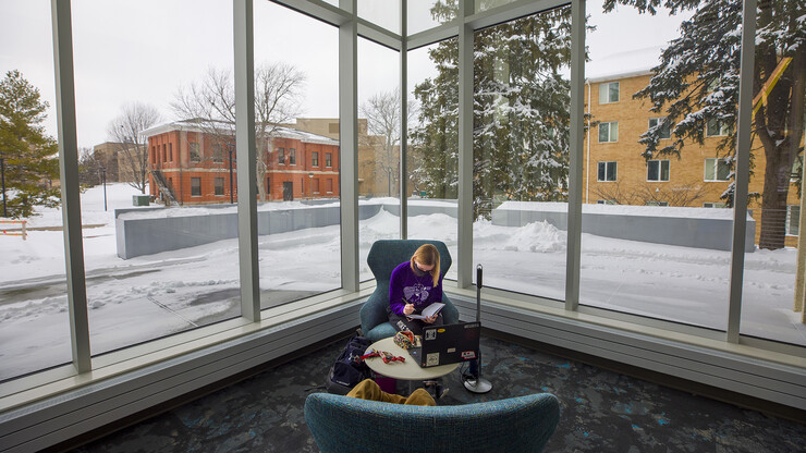 With East Campus at her back, a student studies in the scenic new Dinsdale Learning Commons. Formerly C.Y. Thompson Library, the redesigned space opened Jan. 27.