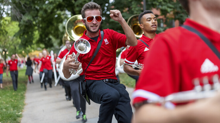 Paul Circo jumps for joy as the Cornhusker Marching Band celebrates while marching to the stadium on Aug. 20.