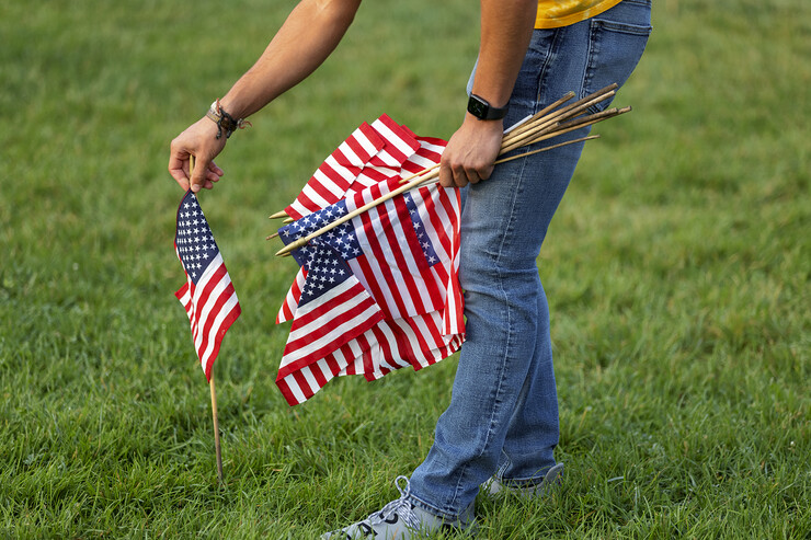 A student places a small flag in the ground north of the Nebraska Union.