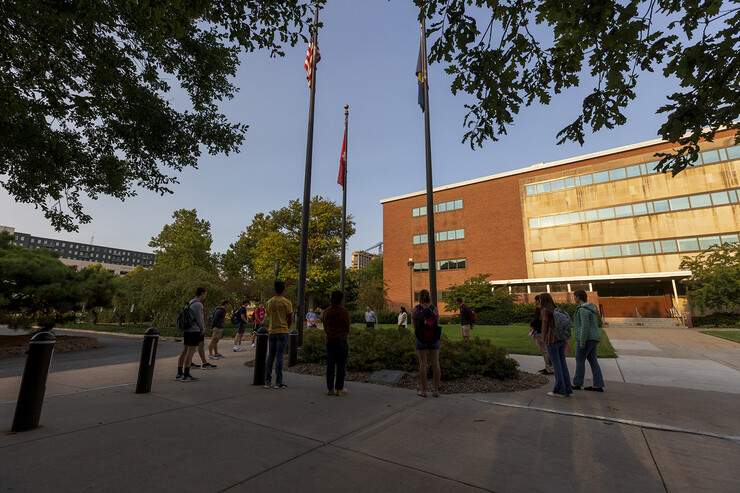Joe Brownell, Director of Military & Veteran Success Center, leads a moment of silence around the flagpole after students set out flags in the green space north of the Nebraska Union.