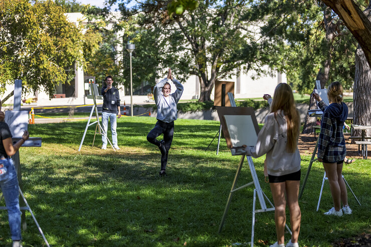 An architecture student strikes a yoga pose as the class participates in a drawing assignment outside of Architecture Hall.