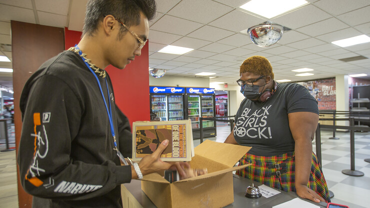 Nebraska's Bianca Swift (right) watches as Tony Nguyen verifies a textbook pre-order from the University Bookstore.
