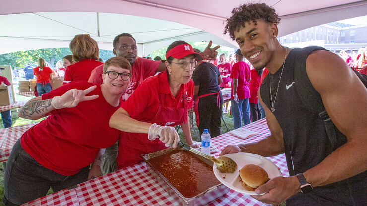 A student (right) poses with Dining Services team members (from left) Julia Guilliams, Osman Sindiga and Joan Mendoza during the chancellor's barbecue on Aug. 19.