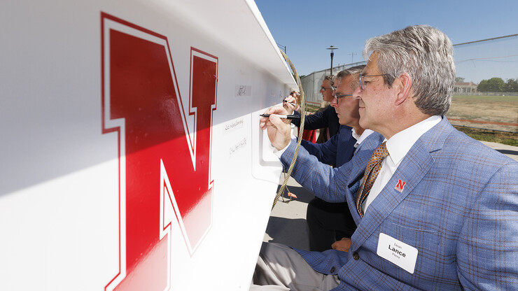 Lance C. Pérez (from right), dean of engineering, Chancellor Ronnie Green, and others sign the beam during the topping out ceremony at the Kiewit Hall site.