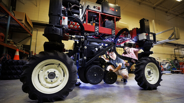 Nebraska’s Santosh Pitla (right), associate professor of biological systems engineering, watches as Chee Town Liew, staff with biological systems engineering, adjusts the height on a planter attachment on a robotic tractor. The tractor is a testbed for automated agriculture and will be used to plant cover crops in the fall.