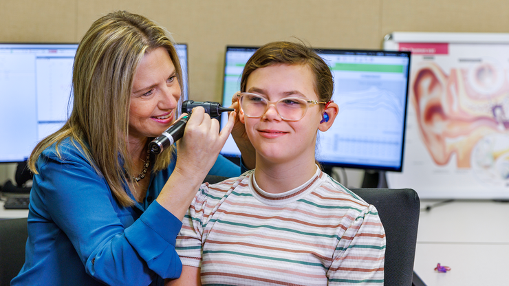 audiologist stacie ray checks the ear of chloie lachance