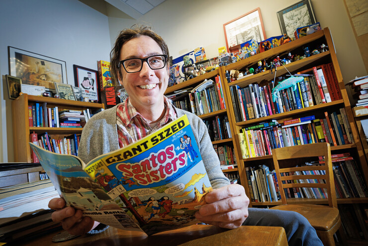 Richard Graham, Associate Professor of University Libraries, sits in his office overflowing with comic culture