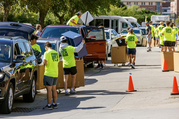 The Student Move-In Team swarms the line of cars outside Abel Residence Hall to unpack their belongings.