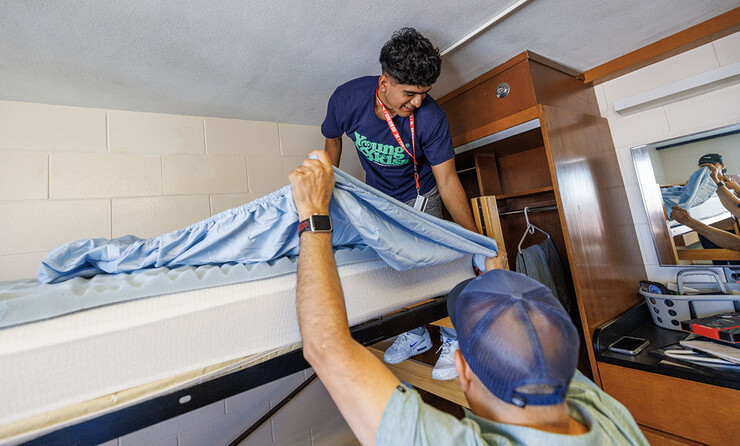 Jose Lopez of Gibbon works on making his bed with help of his dad, Jose, and his sister, Stephanie (in mirror). Jose is majoring in Sports Media in the CoJMC.