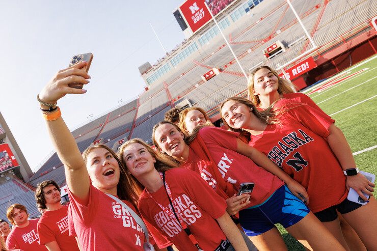 Students take photos on the field during the Tunnel Walk at Memorial Stadium.