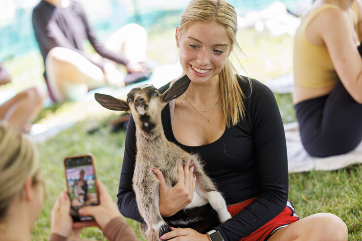 Kyra Jenkins, a freshman from Springfield, Nebraska, poses for a photo with a goat during goat yoga.