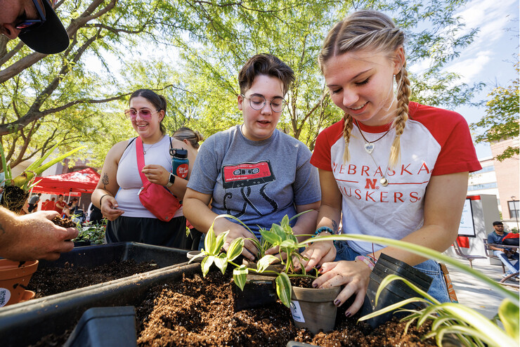 Shae Mitchess, a freshman from Edison, Nebraska, center, and Emmy Oldhan, a freshman from Wellfleet, Nebraska, add potting soil for their plants 