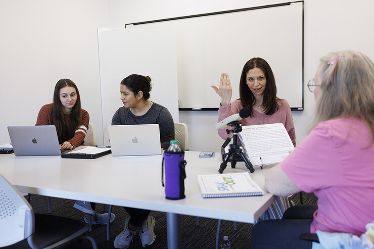 Jessie Kohn, lecturer in Special Education & Communication Disorders, gives instructions to Rhonda Heiserman of Lincoln during her clinic session. The instrument on the table measures the decibel level of her speech.  Graduate students Claire Streeter, left, and Nayeli Cruz takes notes.