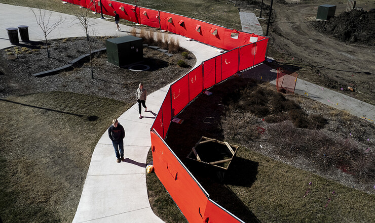 Students walk across East Campus by construction fencing surrounding a plaza renovation project.