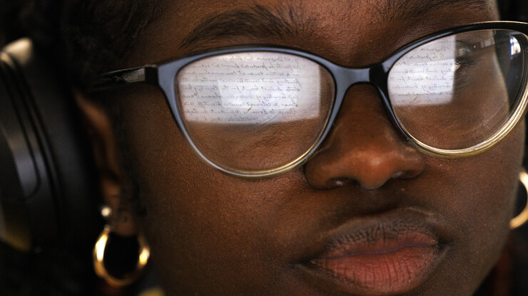 A document is reflected in the glass of Veronica Sargbah, a sophomore from Omaha, as she transcribes the written text.