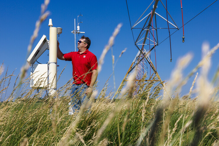 Trenton Franz inspects one of the cosmic ray neutron sensors at UNL's Eastern Nebraska Research, Extension and Education Center near Mead. The sensors' readings indicate soil moisture levels. Solar flares, such as those that produced the auroras in Nebraska on May 10-11, trigger electromagnetic interference in the sensors' readings. UNL has taken steps to correct the distortions and ensure data reliability. 