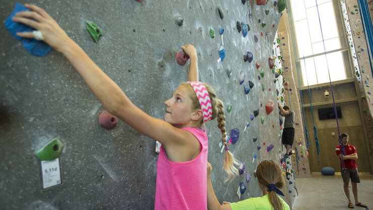 Bright Lights campers cling to the Outdoor Adventures Center climbing wall during a game on June 7. The climbing wall is open 10 a.m. to 8 p.m. weekdays during the summer months.