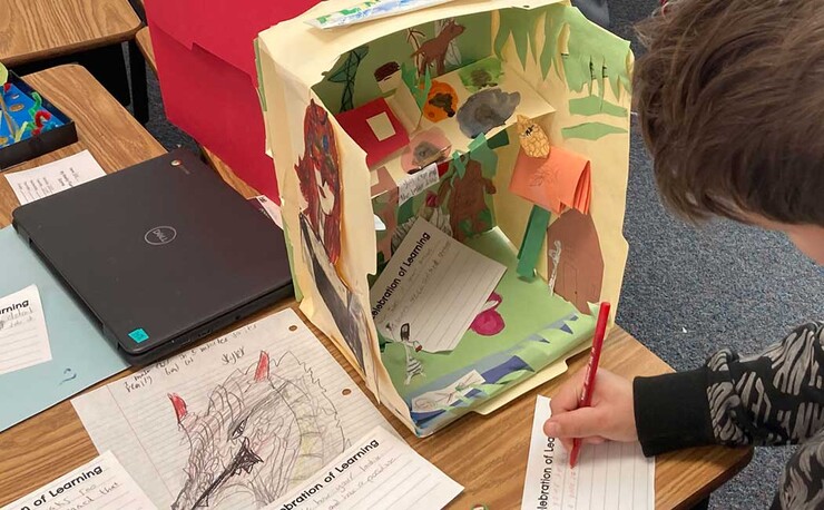 A student offers some peer-to-peer feedback on a project during an Exhibition of Learning. These exhibits are a visual documentation of students’ learning and stem from the Reggio Emilia approach to education.