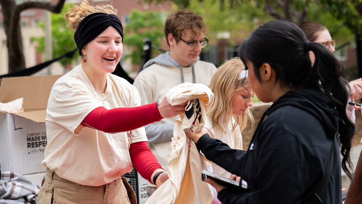 Lily Rippeteau, a junior mathematics and computer science major, hands out T-shirts to student volunteers before the start of the Big Event on May 4.