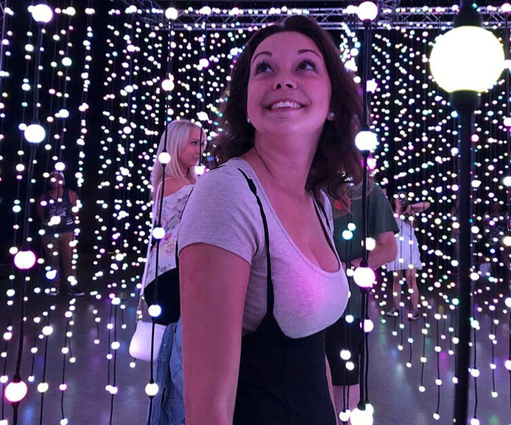 Carly Buser looks up with strings of lights hanging in the background