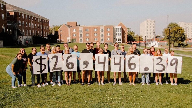 Dance Marathon members hold signs to show the number 26,446.39