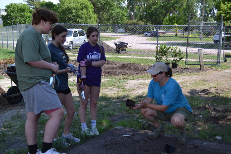 Sarah Buckley, right, instructs FFA members from Battle Creek High School in planting.