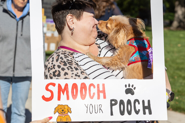 A dog owner kisses her canine while framed by a "Smooch Your Pooch" border