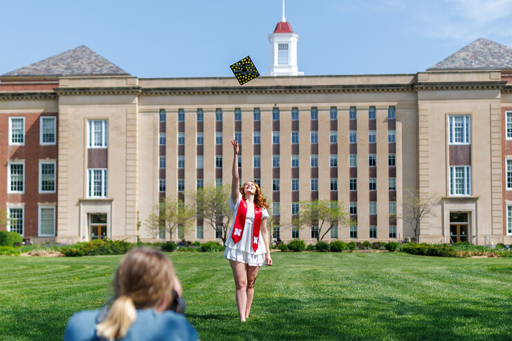 Tessa Sutfin throwing her cap in front of Love Library